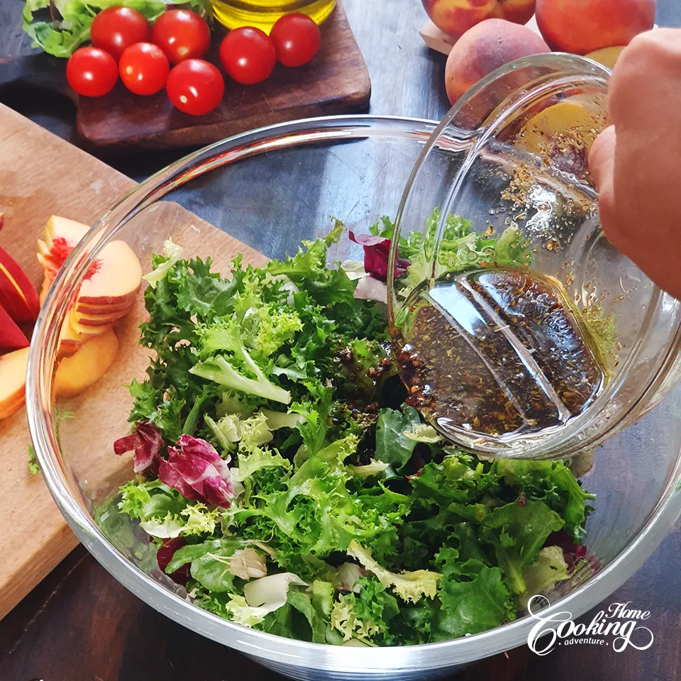 adding the dressing over the leafy greens